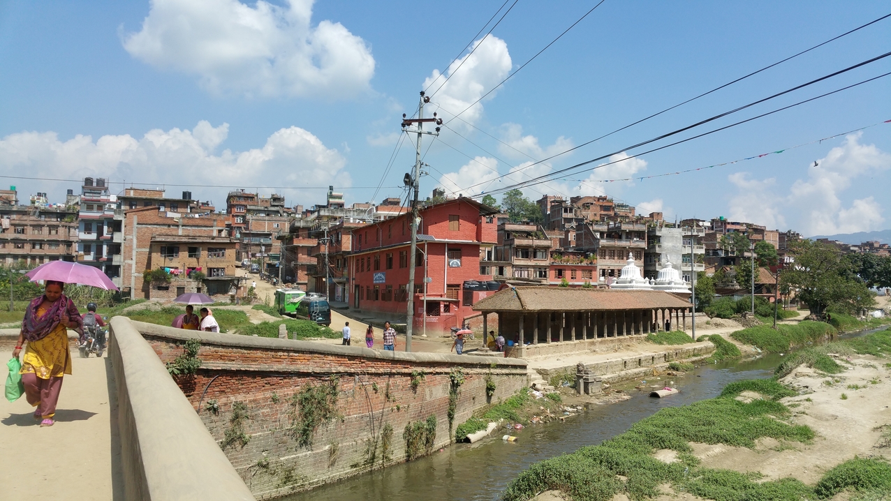 Brücke über den Hanumante Fluss und Blick auf die Glitter Future English Secondary School.
