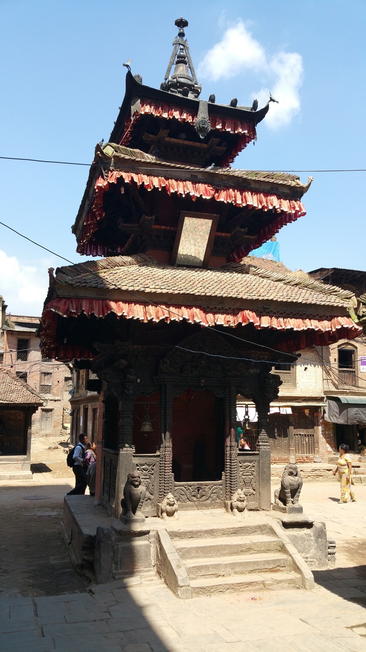 Kleiner Tempel mit Pagodendach und doppelten Türwächtern.
